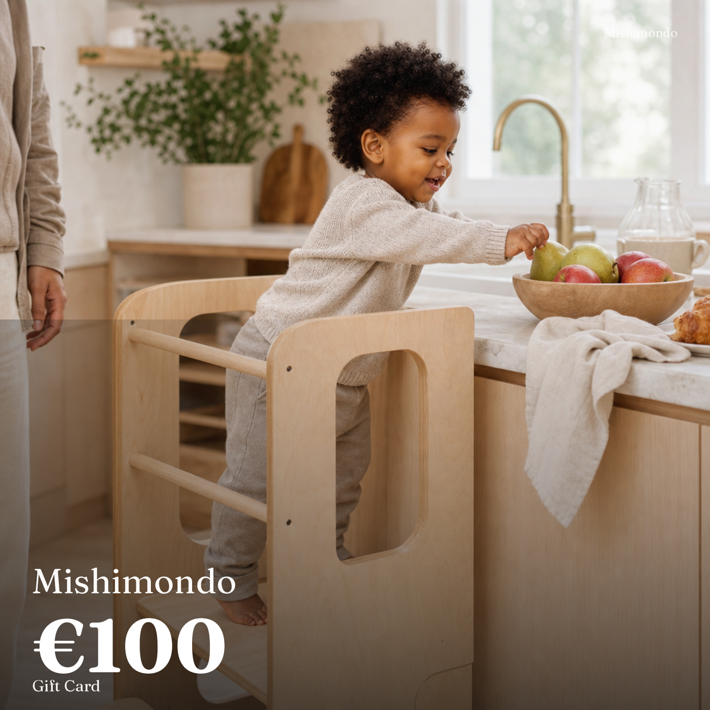 Mishimondo €100 gift card — toddler on a wooden learning tower in the kitchen
